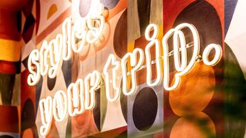 A neon sign with the text 'styles your trip.'