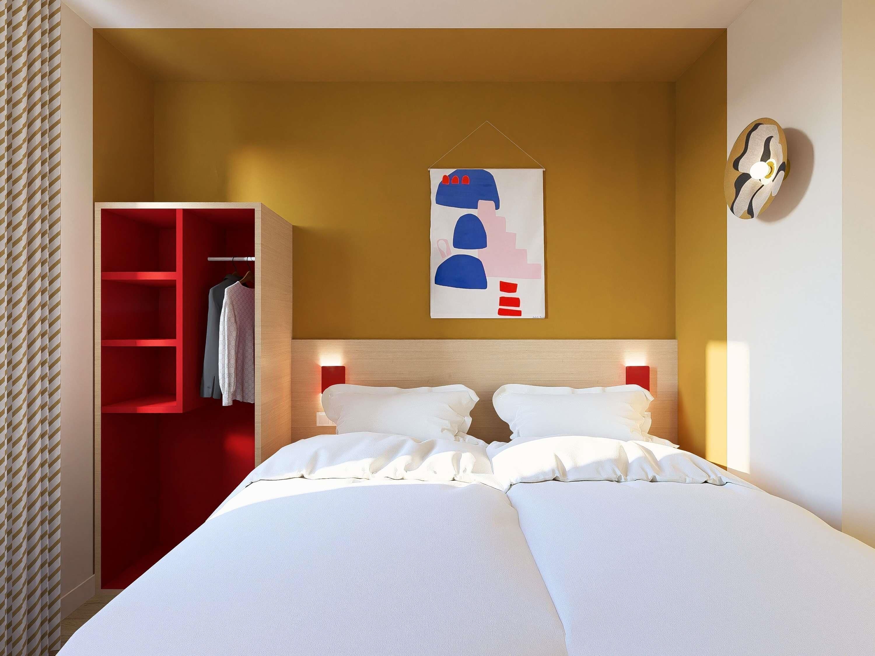 Una habitación de hotel con una cama, un armario y una obra de arte colgada en la pared.