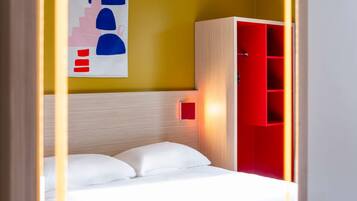 Una habitación con cama, un armario rojo y una pared con diseño geométrico.