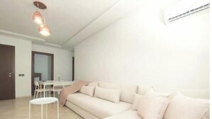 A modern living room with a beige sofa, a small white table, and a ceiling light fixture. - Maison de Luxe Layla (Martil, Tangier-Tétouan-Al Hoceima,)