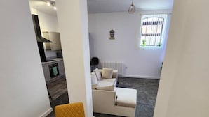 Een moderne woonkamer met een bank, twee gele fauteuils en een glazen salontafel.