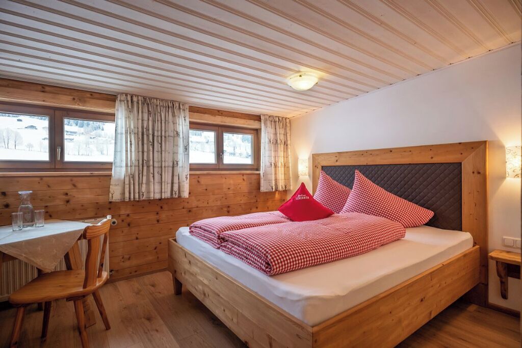 A wooden room with a bed, a table, and a chair.