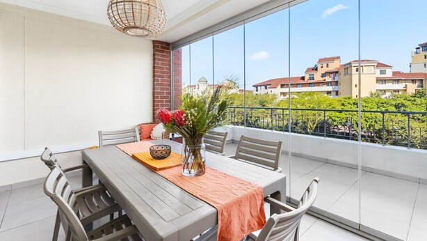 A balcony with a dining table, chairs, a vase with flowers, and a hanging light fixture. - Mayfair 246 (Cape Town)
