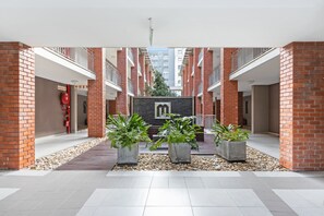 A modern building with red brick walls, a central courtyard with potted plants, and a visible fire hose. - Mayfair 246 (Cape Town)