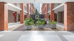 A modern building with red brick walls, a central courtyard with potted plants, and a visible fire hose. - Mayfair 246 (Cape Town)