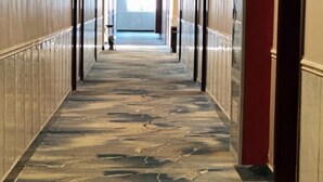 A hallway with a patterned floor and wooden paneling on the walls. - Huaiyuan Huiliang Mingde Hotel (Huaiyuan)