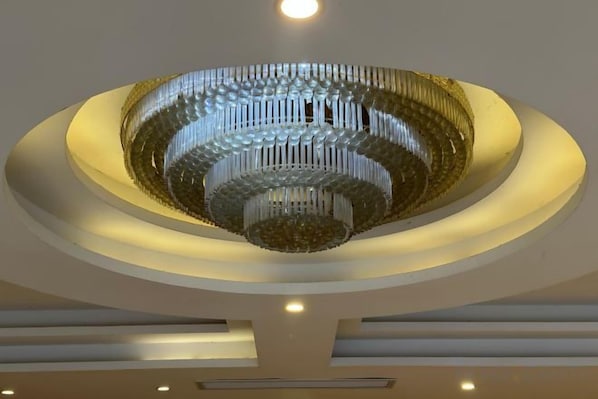 A large, circular chandelier with multiple tiers and lights, centered in a ceiling with recessed lighting.