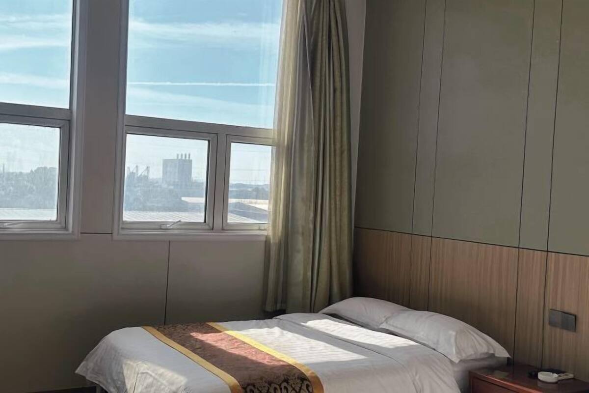 A hotel room with a bed, a nightstand, and a window with curtains.