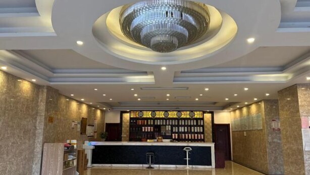 A hotel lobby with a reception desk, a chandelier, and a wall of framed photos. - Huaiyuan Huiliang Mingde Hotel (Huaiyuan)