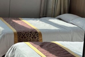 A hotel room with two beds, each with a patterned bedspread and a yellow trim. - Huaiyuan Huiliang Mingde Hotel (Huaiyuan)
