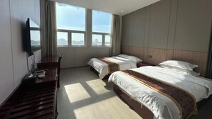 A hotel room with two beds, a desk, a TV, and large windows. - Huaiyuan Huiliang Mingde Hotel (Huaiyuan)