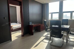 A hotel room with a bed, desk, and chairs. There is a view of the city through large windows. - Huaiyuan Huiliang Mingde Hotel (Huaiyuan)