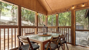 A wooden deck with a glass-top table and chairs, surrounded by large windows. - 4 Master Suites! By StoneBridge Pool! SDC! (Branson West)