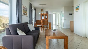 Ein modernes Wohnzimmer mit einer Couch, einem Holztisch und einem Essbereich mit Stühlen und einem Schrank.