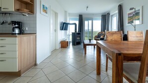 Eine moderne Küche mit Kaffeemaschine, Holzschränken und einem Essbereich mit Holztisch und -stühlen.