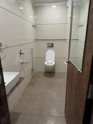 A small, modern bathroom with a toilet, sink, and shower. - Hotel My Budget (Ujjain)