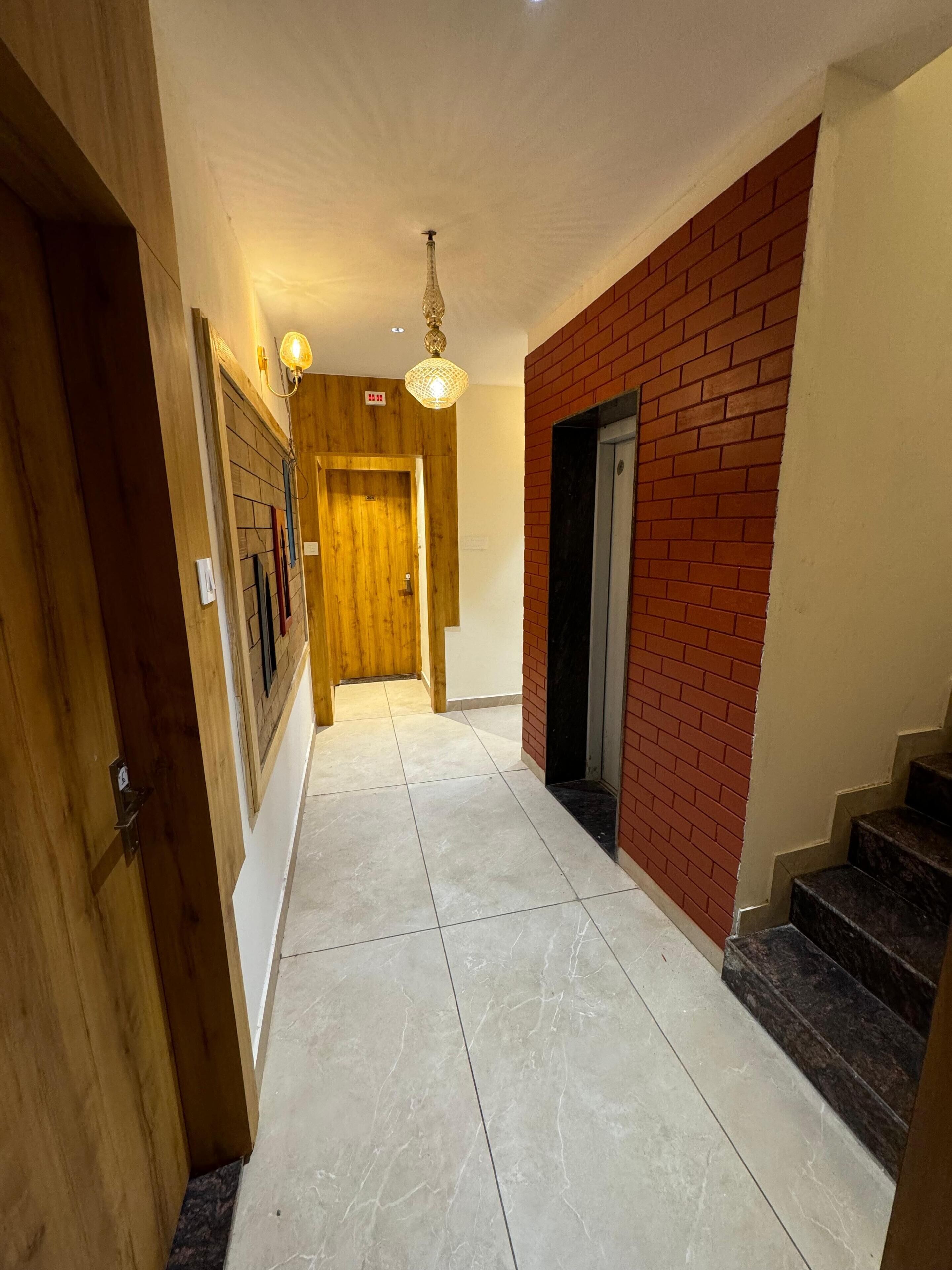 A hallway with a wooden door, a brick wall, and a staircase.