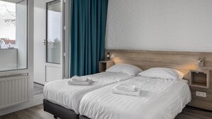 Un letto matrimoniale con biancheria bianca, una testiera in legno e due comodini con lampade.