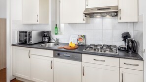 A modern kitchen with white cabinets, a stainless steel range, a coffee maker, and a toaster.
