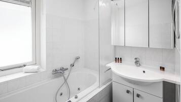 A modern bathroom with a bathtub, a shower, and a sink.