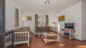 Un salon chaleureux avec un canapé, une table basse, un téléviseur et une cheminée.