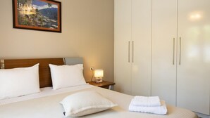 Une chambre d’hôtel avec un grand lit, une table de chevet avec une lampe, une armoire et un tableau encadré au mur.