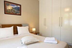 Une chambre d’hôtel avec un grand lit, une table de chevet avec une lampe, une armoire et un tableau encadré au mur.
