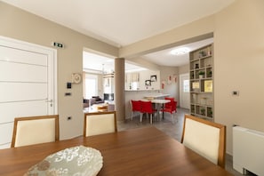 Een eethoek met een houten tafel en rode stoelen, een keuken op de achtergrond en een witte radiator aan de rechterkant.