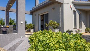 Un bâtiment moderne avec une façade en béton, une porte et des plantes en pot.