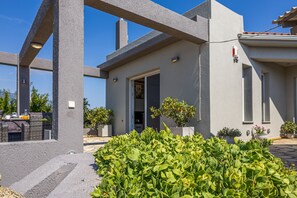 A modern building with a concrete facade, a door, and potted plants. - Tselepis Villa at Lakithra (Kefalonia)