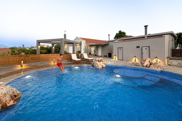 A swimming pool with a stone border and a wooden deck.