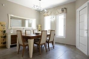 A dining area with a wooden table and chairs, a large mirror, and a chandelier.