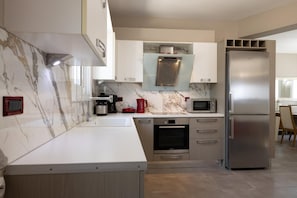 A modern kitchen with a marble backsplash, stainless steel appliances, and light wood cabinetry.