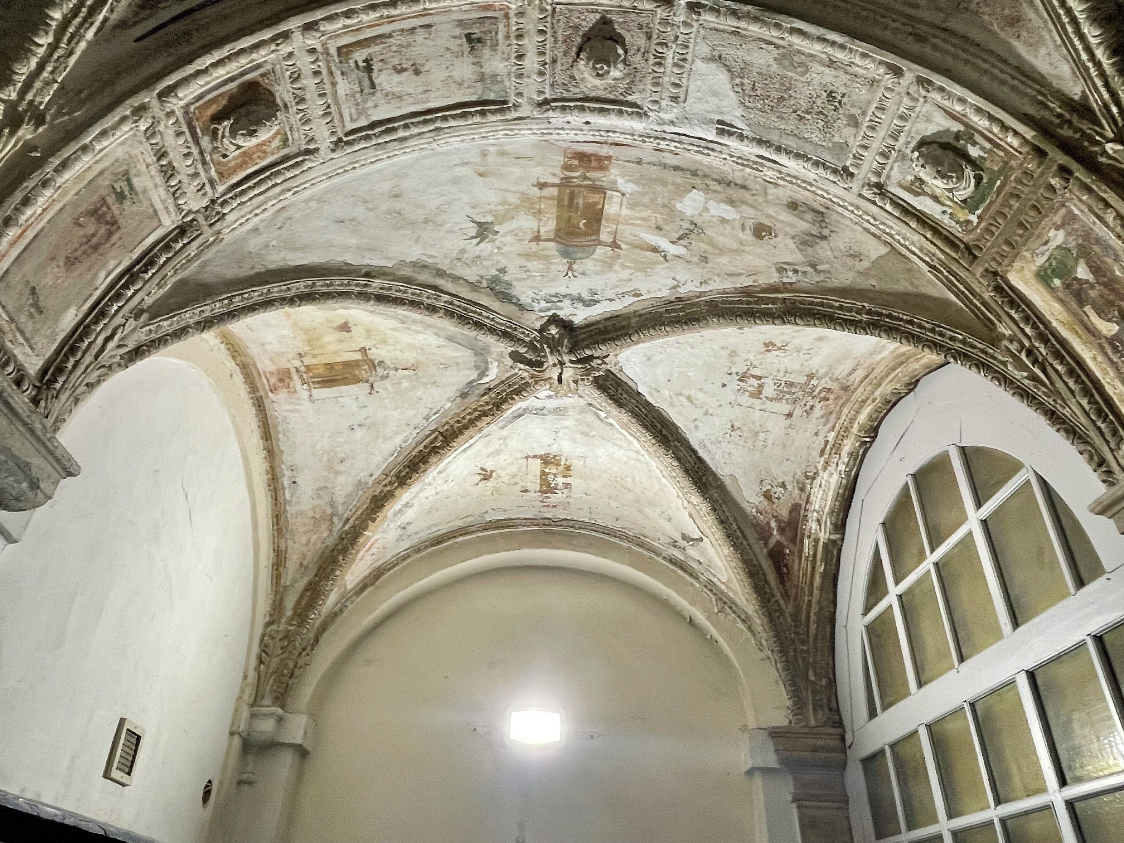An arched ceiling with intricate carvings and a central window.