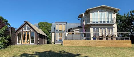 A modern two-story house with a large balcony and a separate garage.
