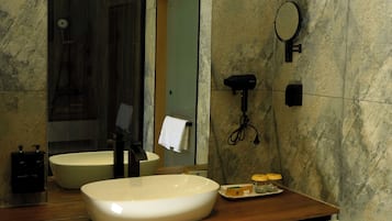 A modern bathroom with a large freestanding sink, a mirror, and a handheld showerhead.