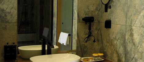 Un baño moderno con un lavamanos independiente grande, un espejo y un cabezal de ducha manual.