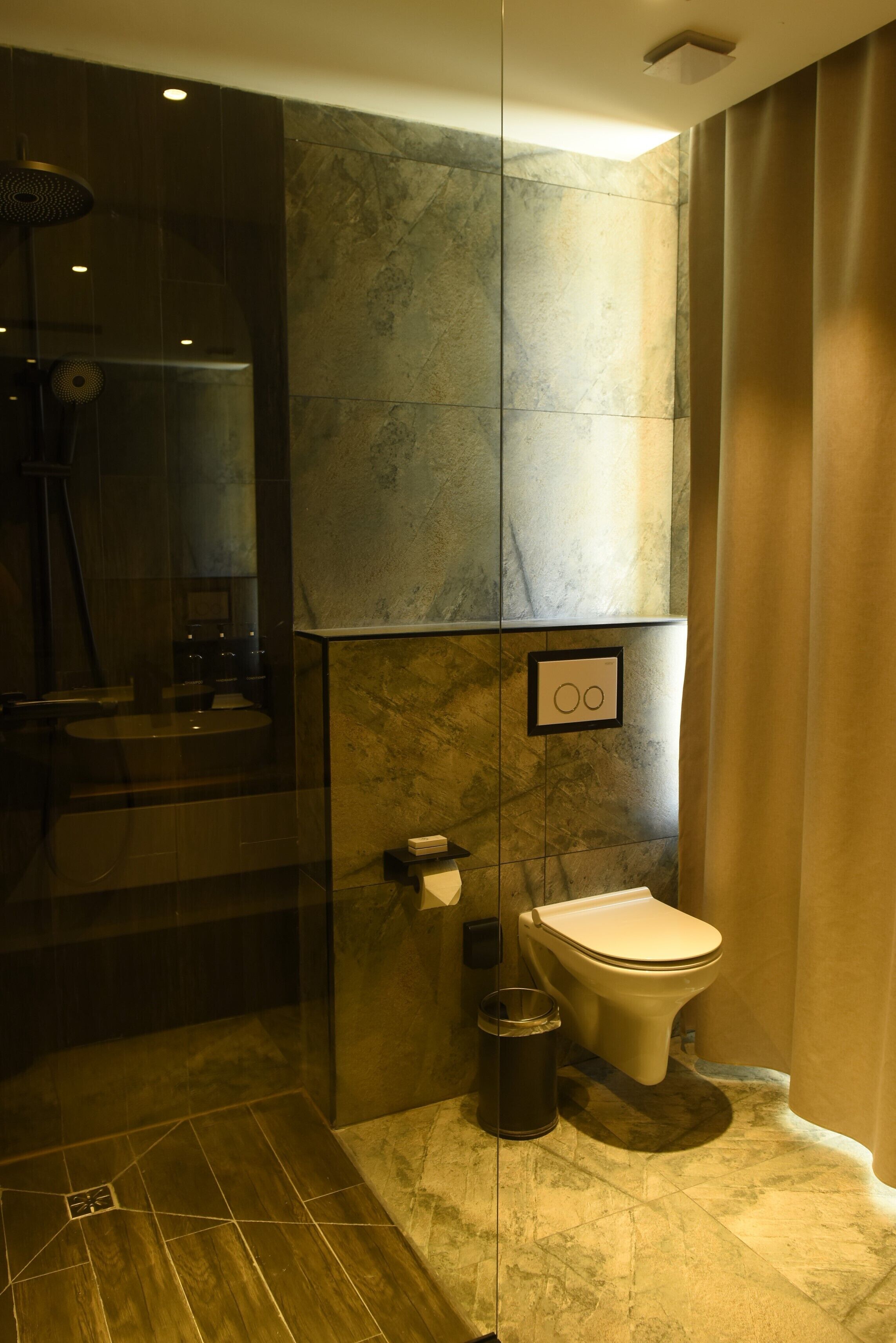 Un bagno moderno con cabina doccia in vetro, un water e un cestino.