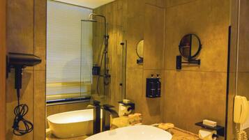 Un baño moderno con un espejo grande, una bañera independiente y un tocador con lavamanos.