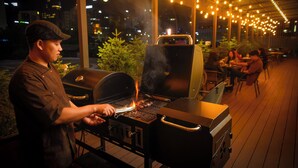 A person grilling outdoors at night with string lights overhead. - Ulaanbaatar Hotel (Ulaanbaatar)