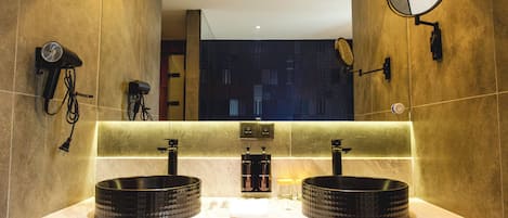 A bathroom with two sinks, a mirror, and a hairdryer on the wall.