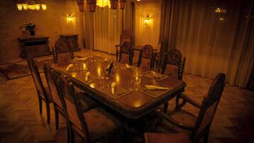 Un comedor formal con una amplia mesa rectangular, sillas ornamentales y una araña.