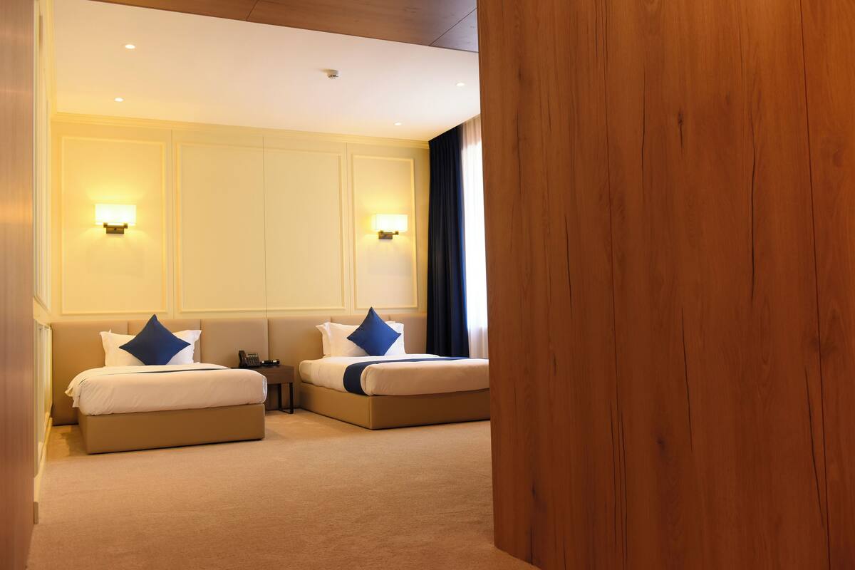 A hotel room with two beds, a desk, and a phone.
