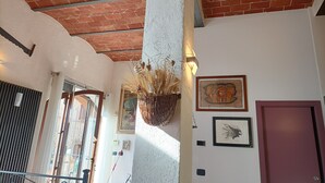A room with a brick ceiling, a white column, a hanging plant, and framed artwork on the walls. - Open space studio apartment with patio near Siena (Monteriggioni)