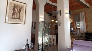 A room with a brick ceiling, a framed ancient Egyptian artifact, a glass cabinet with bottles, and a purple sofa. - Open space studio apartment with patio near Siena (Monteriggioni)