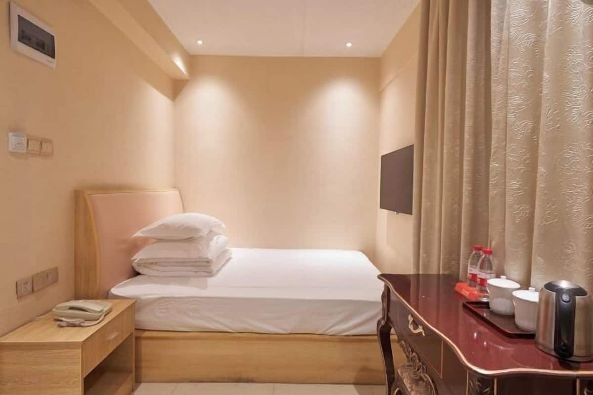 Une chambre d’hôtel équipée d’un lit, d’une table de chevet et d’un bureau avec une bouilloire et des tasses.