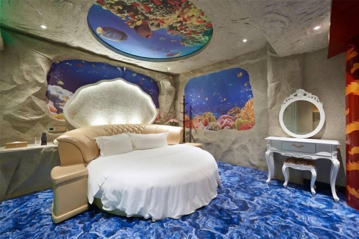 Une chambre à coucher comprenant un lit, une coiffeuse, un miroir et une peinture murale au plafond.
