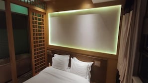 Une chambre d’hôtel avec un lit, une cloison en bois et un luminaire fixé au mur.