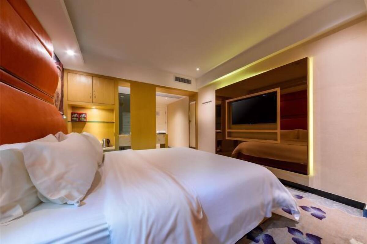 Une chambre d’hôtel avec un lit, une télévision et une armoire en bois.