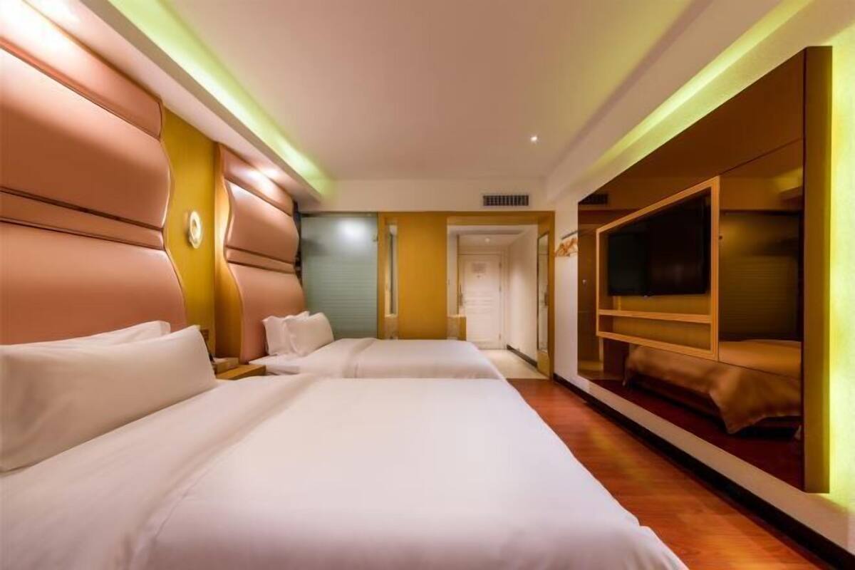 Une chambre d’hôtel avec deux lits, une télévision et une porte donnant sur une autre pièce.